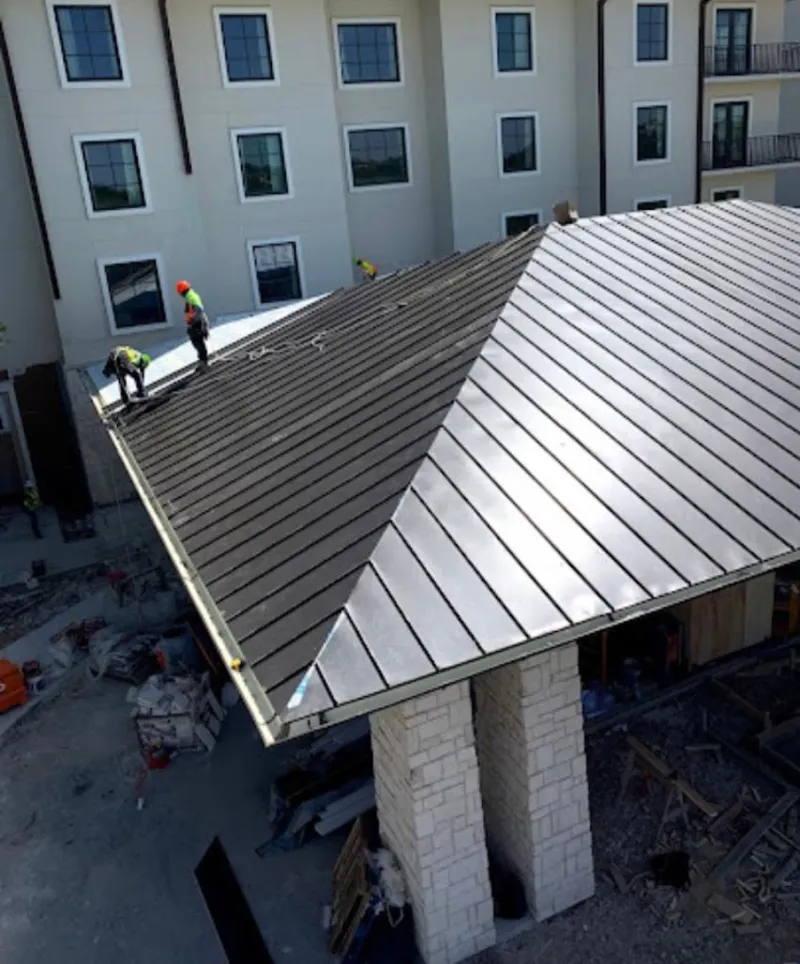 Crew installing standing seam metal roof panels on a commercial project in Hamilton